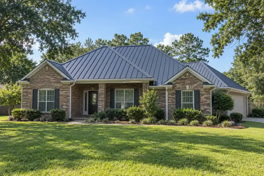 Charcoal standing-seam roof with straight raised seams and white gutters on a brick house